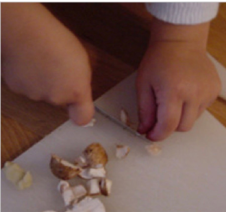 A child's hands cutting mushrooms on a cutting board during a research session